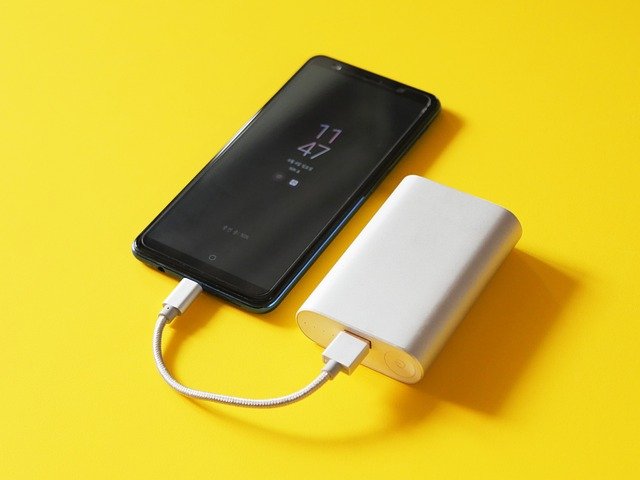 Bateria de smartphone sobre superfície escura, ilustrando degradação de bateria como causa de travamento no iPhone