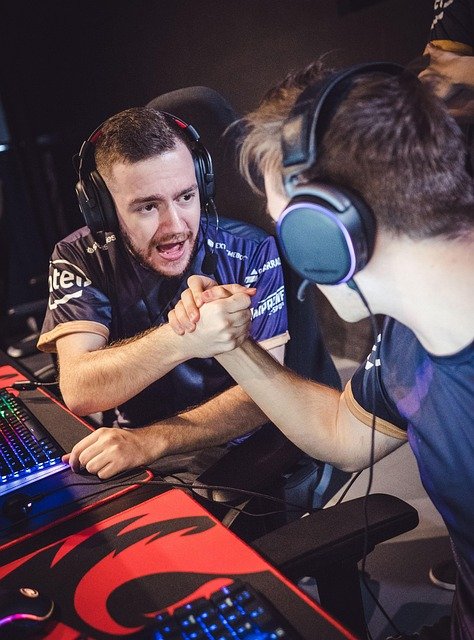 Pessoas jogando em computadores gamer lado a lado